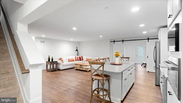 a kitchen with stainless steel appliances a dining table chairs and wooden floor