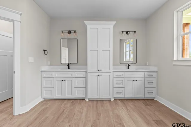 a spacious bathroom with double vanity a mirror a bathtub and double vanity