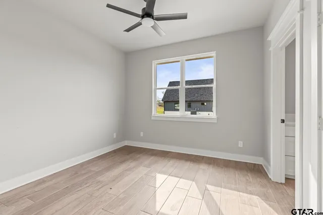 a view of an empty room with a window and wooden floor