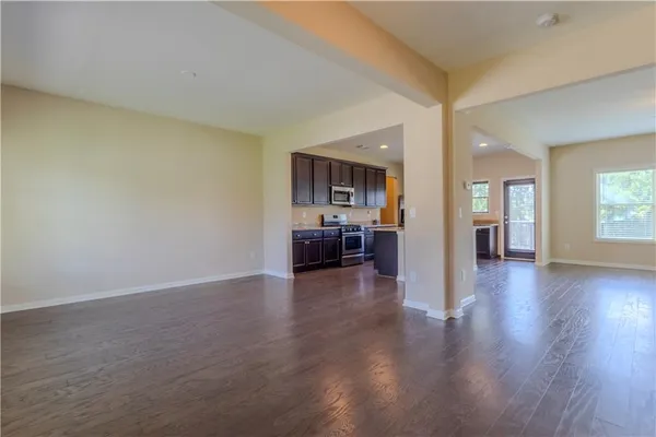 a view of a big room with wooden floor and a kitchen