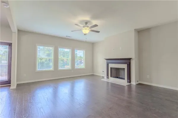 a view of an empty room with a window and wooden floor