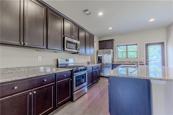 a kitchen with stainless steel appliances granite countertop wooden cabinets a stove top oven a sink and dishwasher