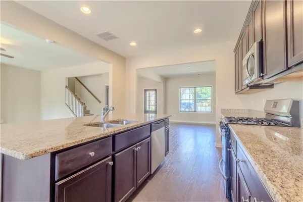 a kitchen with granite countertop a sink a stove and cabinets