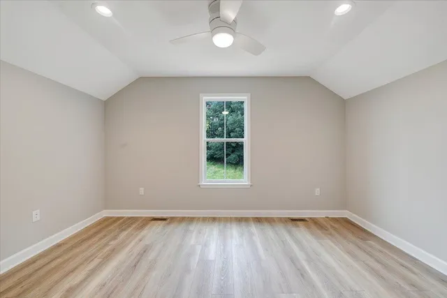 an empty room with windows and ceiling fan