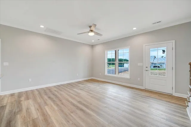 an empty room with wooden floor and windows