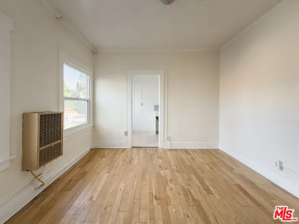 a view of an empty room with a window and wooden floor