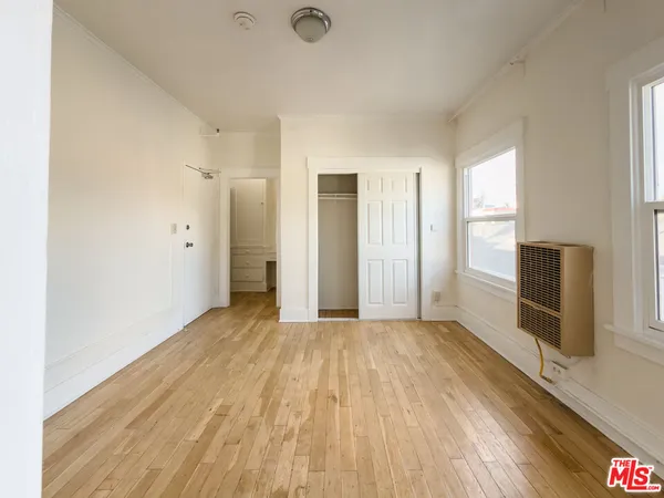 a view of empty room with wooden floor and fan
