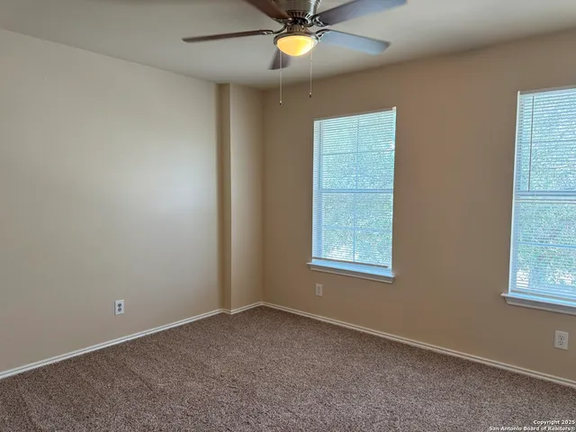 an empty room with chandelier fan and hallway