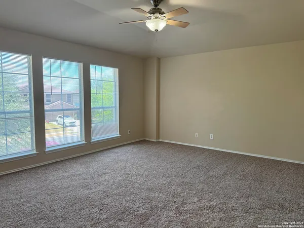 a view of an empty room with a chandelier fan