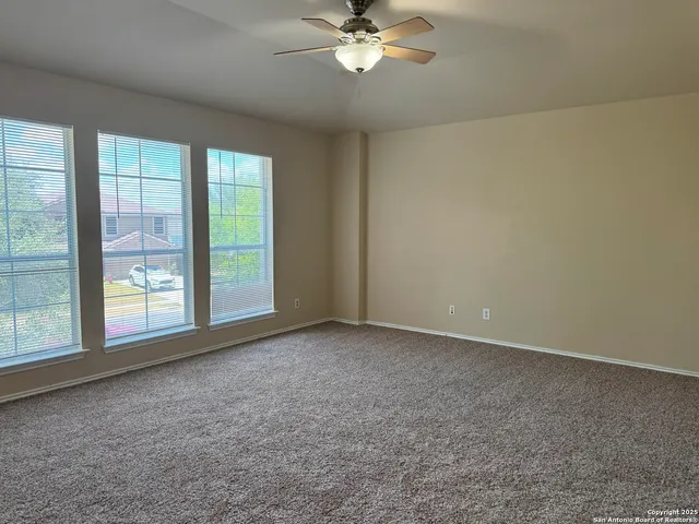 a view of an empty room with a chandelier fan