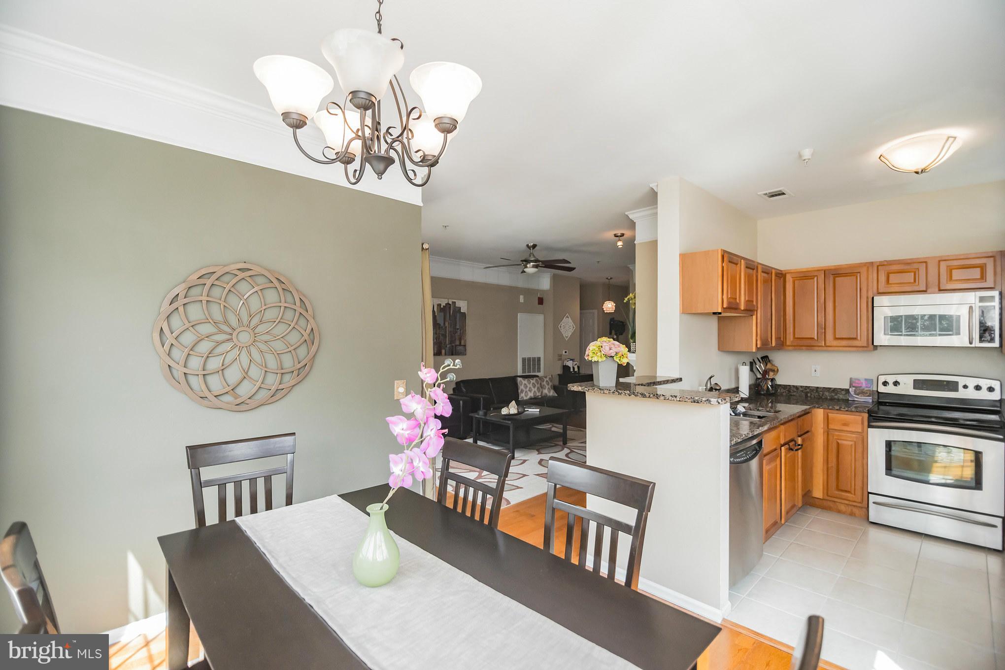 1600 Spring Gate Dr., Unit 2215 McLean, VA 22102 - Photo 12 of 30 a kitchen with stainless steel appliances granite countertop a stove top oven a dining table and chairs with wooden floor