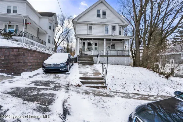 a front view of a house with a yard covered in snow