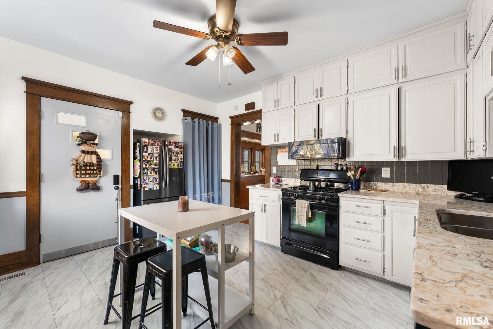 308 Northeast 3rd Avenue Aledo, IL 61231 - Photo 9 of 28 a kitchen with stainless steel appliances kitchen island granite countertop a stove a refrigerator a sink a dining table and chairs with wooden floor