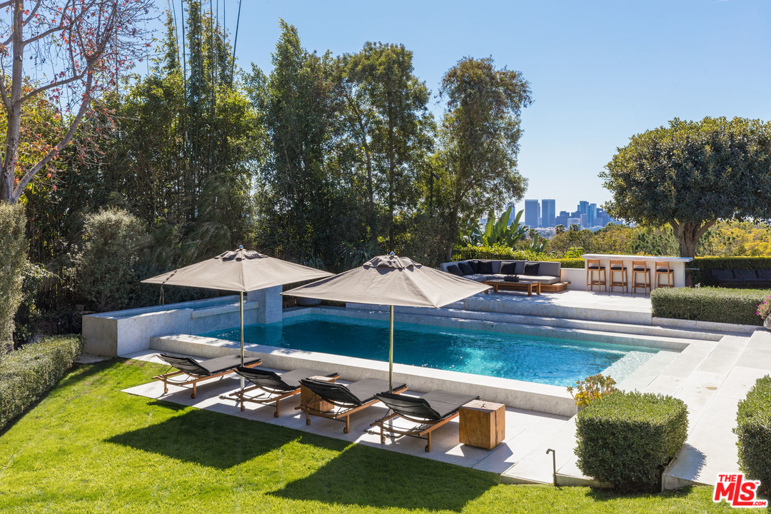 North Hillcrest Road Beverly Hills, CA 90210 - Photo 26 of 34 a view of a swimming pool with a table and chairs under an umbrella