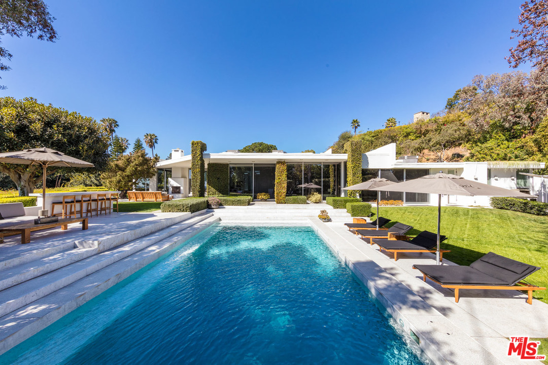 North Hillcrest Road Beverly Hills, CA 90210 - Photo 28 of 34 a view of a swimming pool with lawn chairs under an umbrella