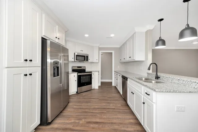 a kitchen with stainless steel appliances granite countertop a refrigerator a sink a stove and oven