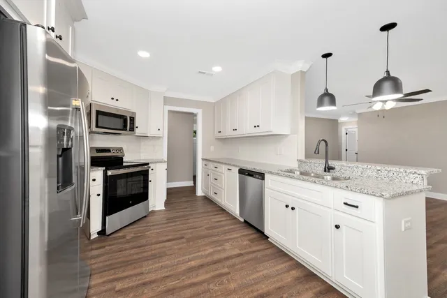 a kitchen with kitchen island granite countertop a sink stainless steel appliances and cabinets