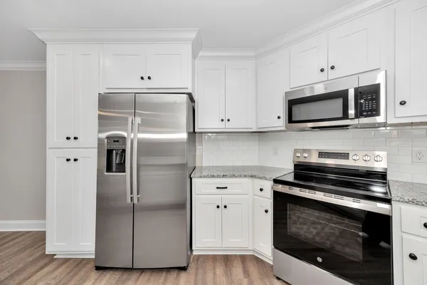 a kitchen with cabinets stainless steel appliances and wooden floor