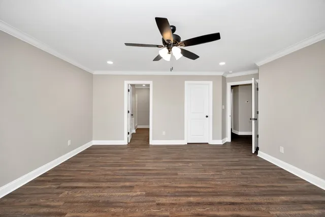 a view of an empty room with wooden floor and a ceiling fan