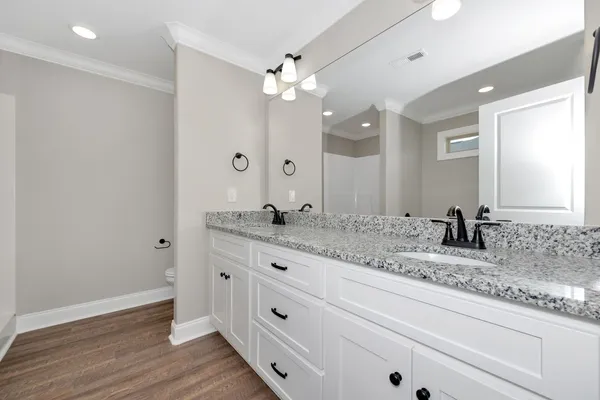 a bathroom with a granite countertop double vanity sink and mirror