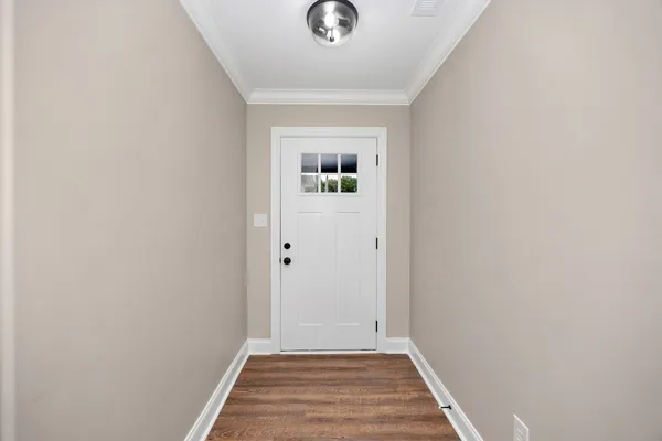 a view of a hallway with wooden floor and a white door