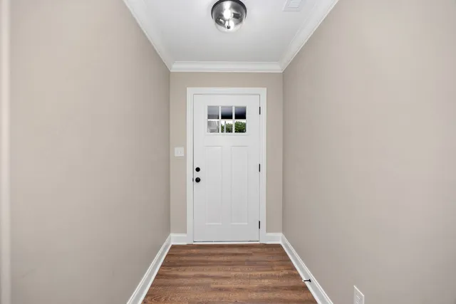 a view of a hallway with wooden floor and a white door