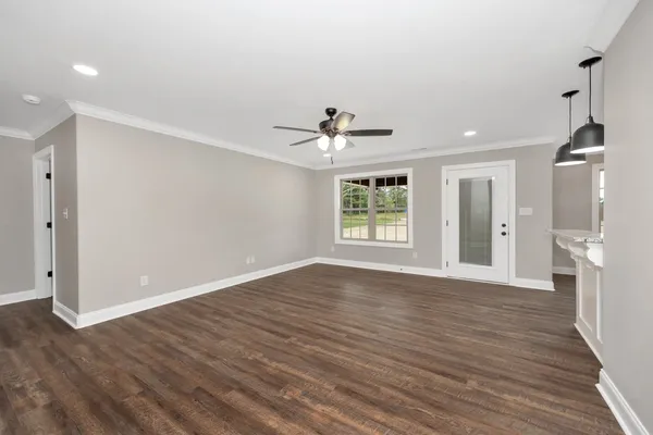 a view of an empty room with wooden floor and a window