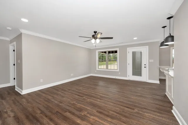 a view of an empty room with wooden floor and a window