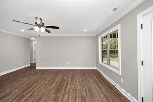 a view of an empty room with wooden floor and a window