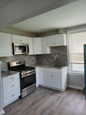 a kitchen with granite countertop white cabinets and black appliances