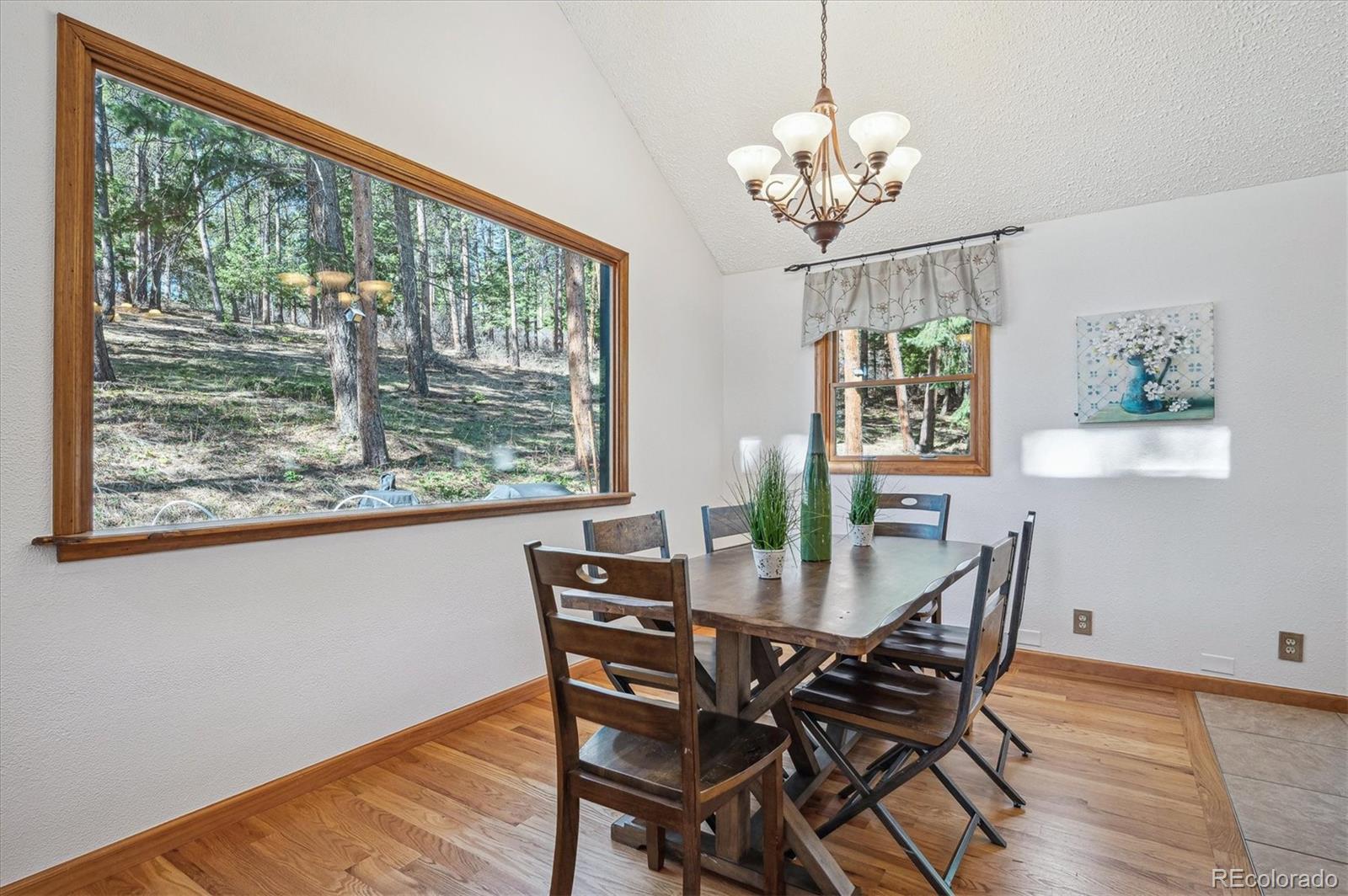 20025 Flint Lane Morrison, CO 80465 - Photo 5 of 35 a view of a dining room with furniture a chandelier and wooden floor