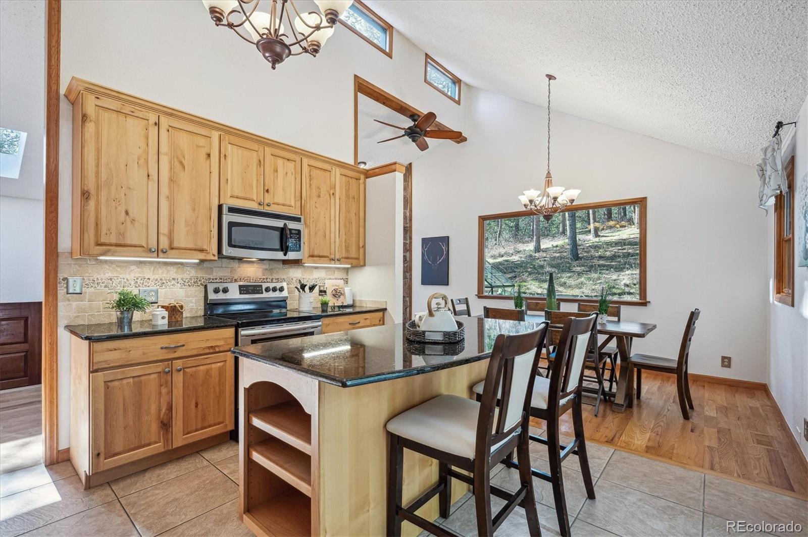20025 Flint Lane Morrison, CO 80465 - Photo 9 of 35 a kitchen with kitchen island granite countertop a table chairs microwave and cabinets