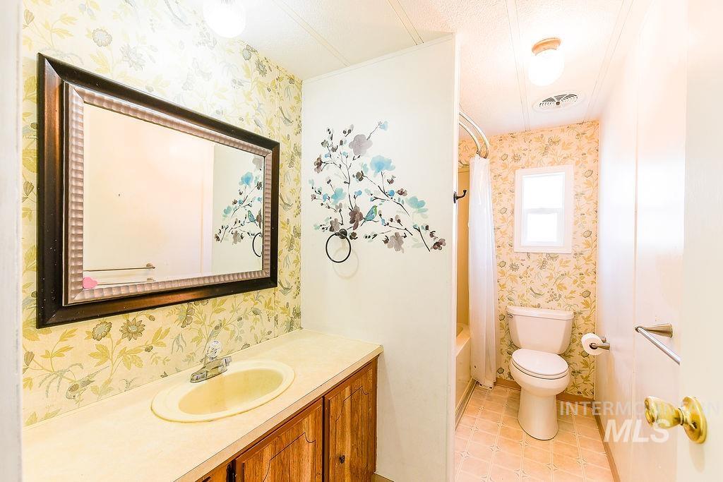 609 North Almon Street, Unit 2011 Moscow, ID 83843 - Photo 11 of 45 Full bathroom featuring vanity, wallpapered walls, shower / bath combo with shower curtain, and light tile patterned floors