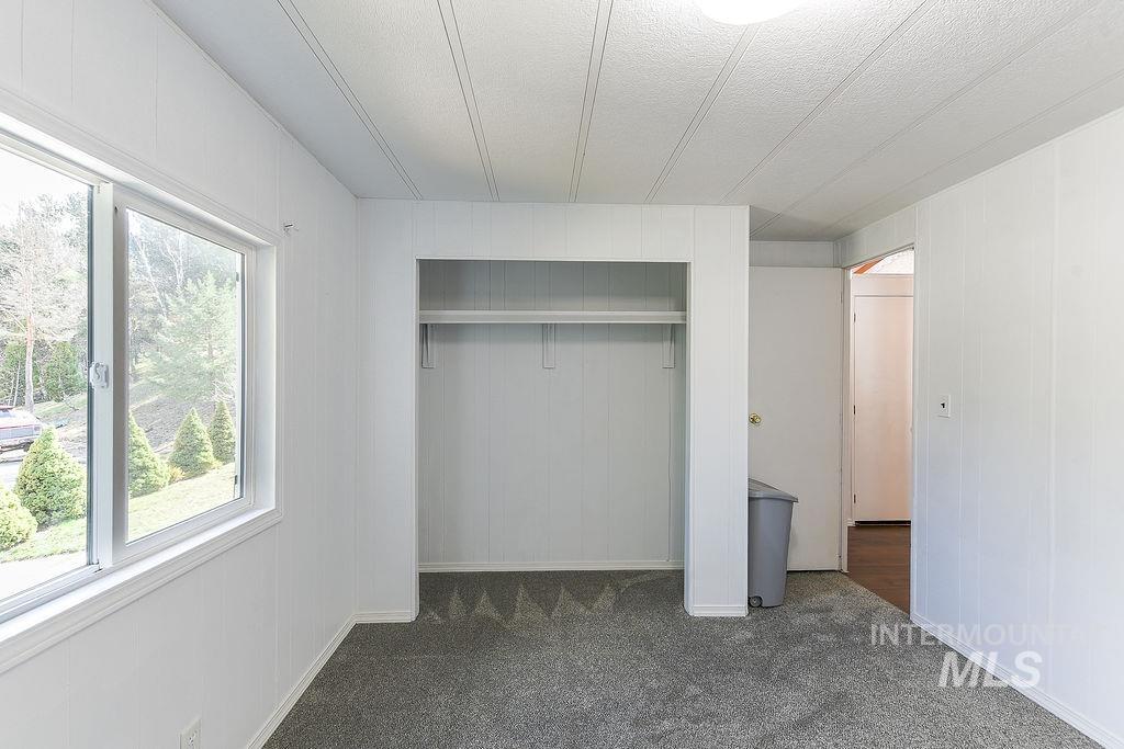 609 North Almon Street, Unit 2011 Moscow, ID 83843 - Photo 13 of 45 Unfurnished bedroom with a closet, dark carpet, wooden walls, and a textured ceiling