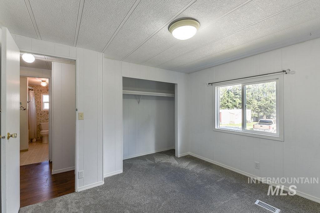 609 North Almon Street, Unit 2011 Moscow, ID 83843 - Photo 15 of 45 Unfurnished bedroom with a closet, dark colored carpet, a textured ceiling, and wooden walls