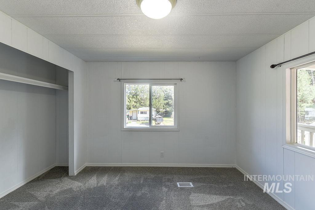 609 North Almon Street, Unit 2011 Moscow, ID 83843 - Photo 16 of 45 Unfurnished bedroom with dark carpet, wood walls, a textured ceiling, and a closet