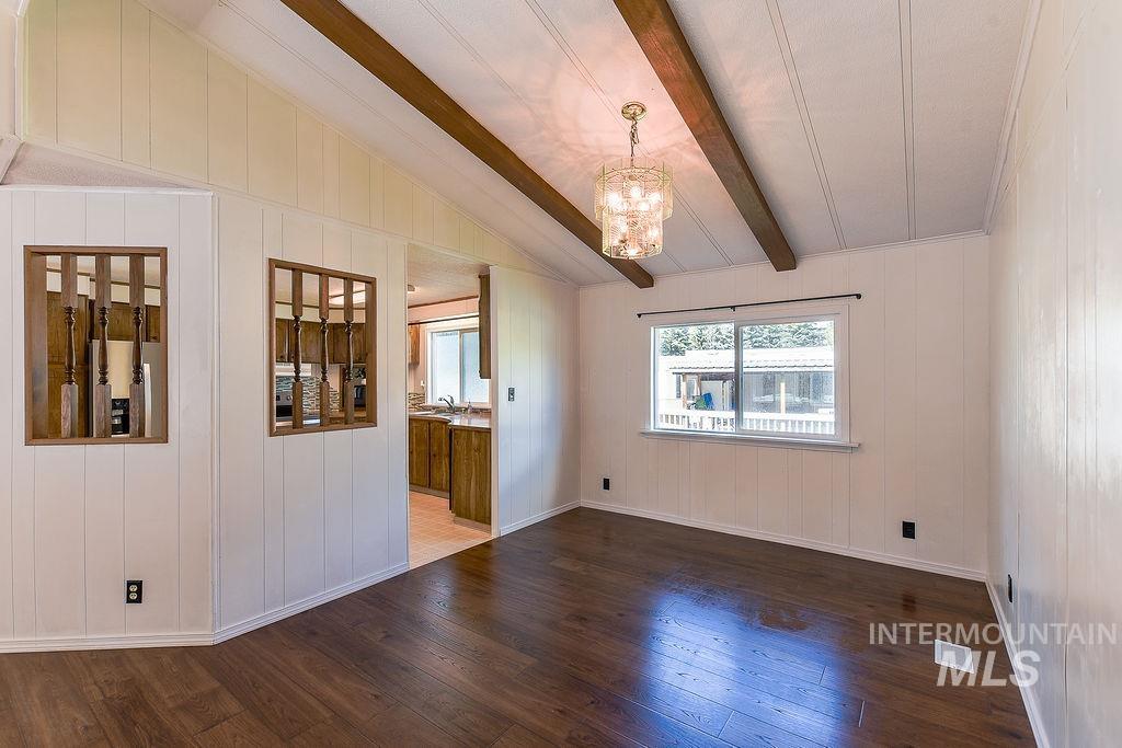 609 North Almon Street, Unit 2011 Moscow, ID 83843 - Photo 17 of 45 Unfurnished dining area featuring a chandelier, dark wood finished floors, wood walls, and lofted ceiling with beams