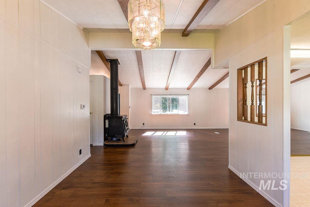 609 North Almon Street, Unit 2011 Moscow, ID 83843 - Photo 19 of 45 Unfurnished living room with beamed ceiling, dark wood-style floors, hanging lights, wood walls, and a wood stove