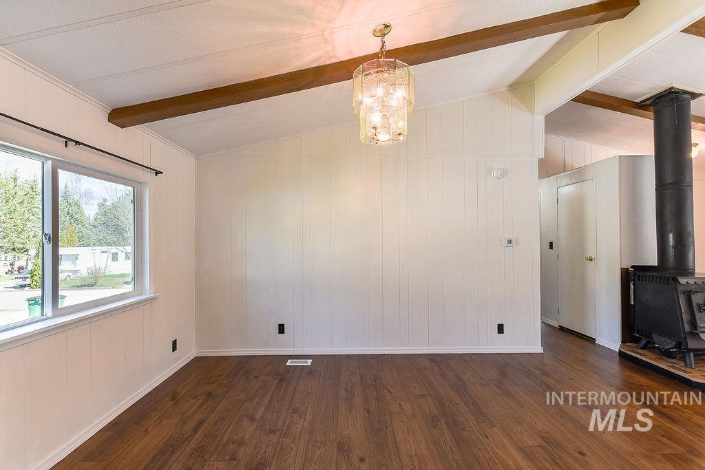 609 North Almon Street, Unit 2011 Moscow, ID 83843 - Photo 20 of 45 Unfurnished dining area with dark wood-style flooring, suspended lighting, wood walls, lofted ceiling with beams, and a wood stove
