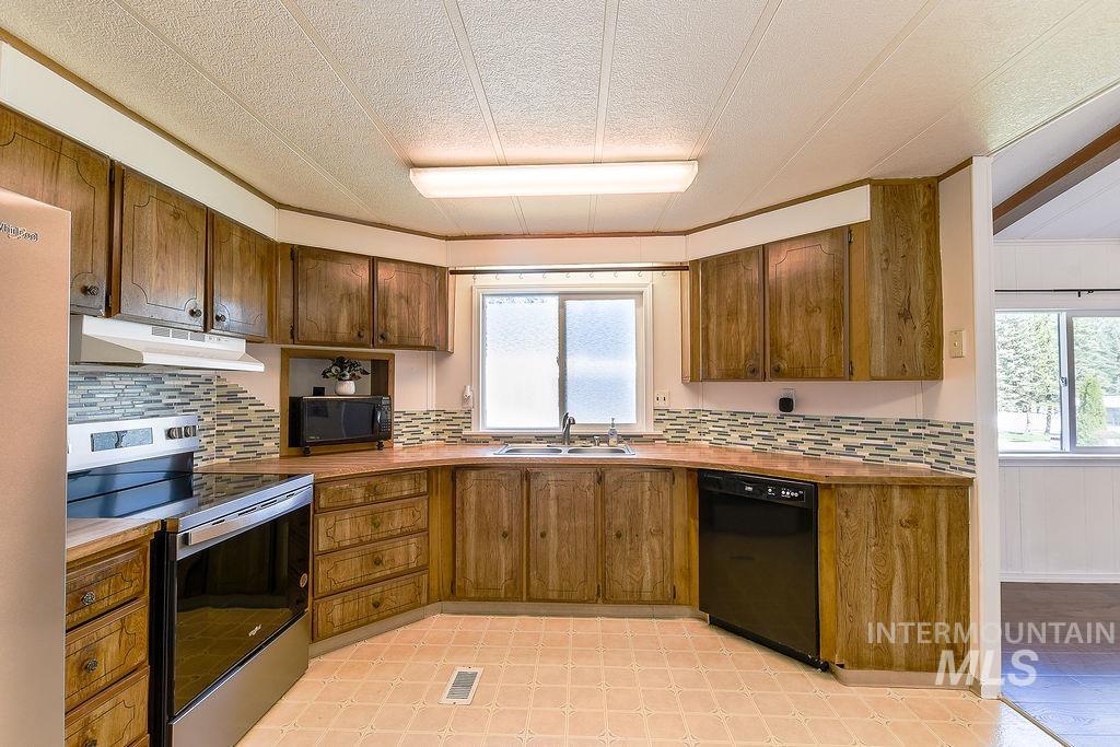 609 North Almon Street, Unit 2011 Moscow, ID 83843 - Photo 21 of 45 Kitchen with black appliances, a textured ceiling, healthy amount of natural light, wood finish cabinets, and decorative backsplash