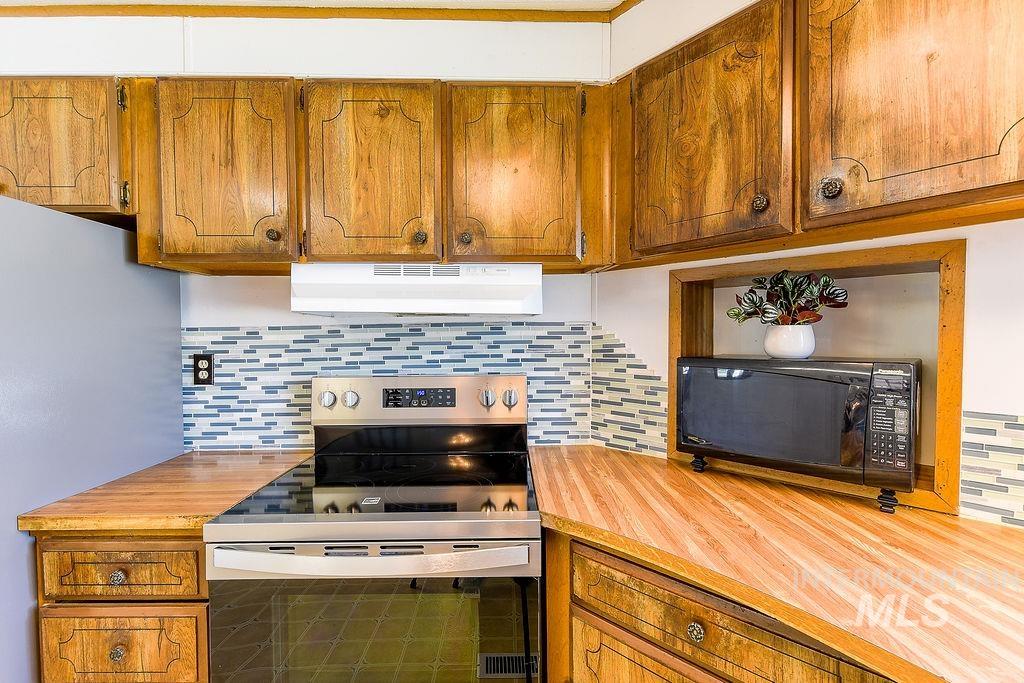 609 North Almon Street, Unit 2011 Moscow, ID 83843 - Photo 24 of 45 Kitchen featuring wood finish cabinetry, stainless steel range with electric cooktop, tasteful backsplash, and freestanding refrigerator