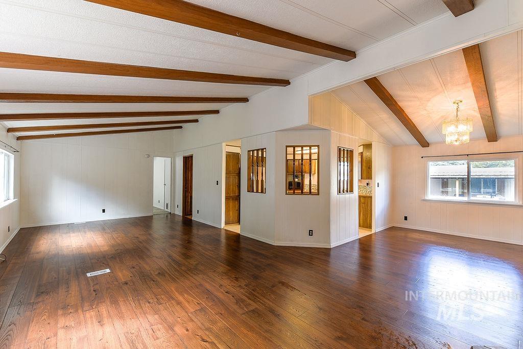 609 North Almon Street, Unit 2011 Moscow, ID 83843 - Photo 5 of 45 Unfurnished living room featuring lofted ceiling with beams, dark wood-type flooring, and suspended lighting