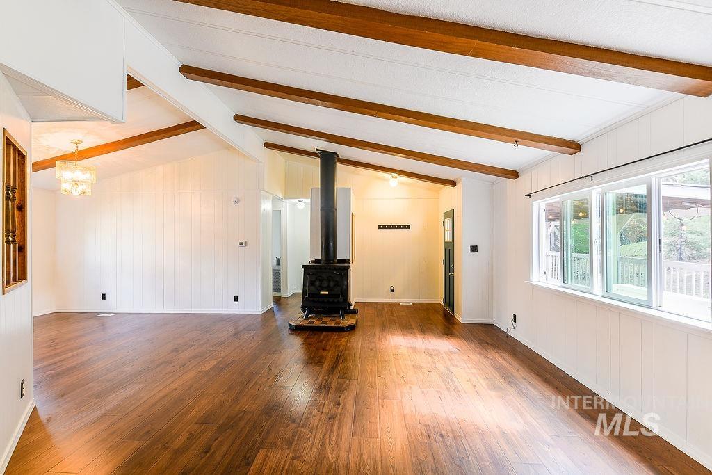 609 North Almon Street, Unit 2011 Moscow, ID 83843 - Photo 9 of 45 Unfurnished living room featuring dark wood finished floors, a wood stove, wooden walls, and lofted ceiling with beams
