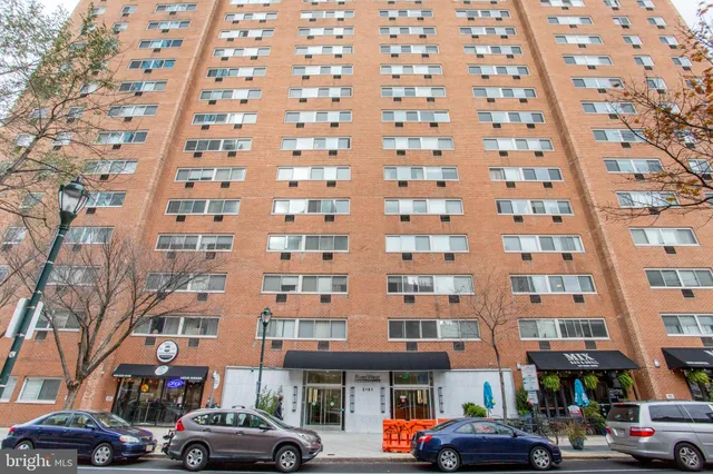 a front view of a building with lot of cars parked on city street