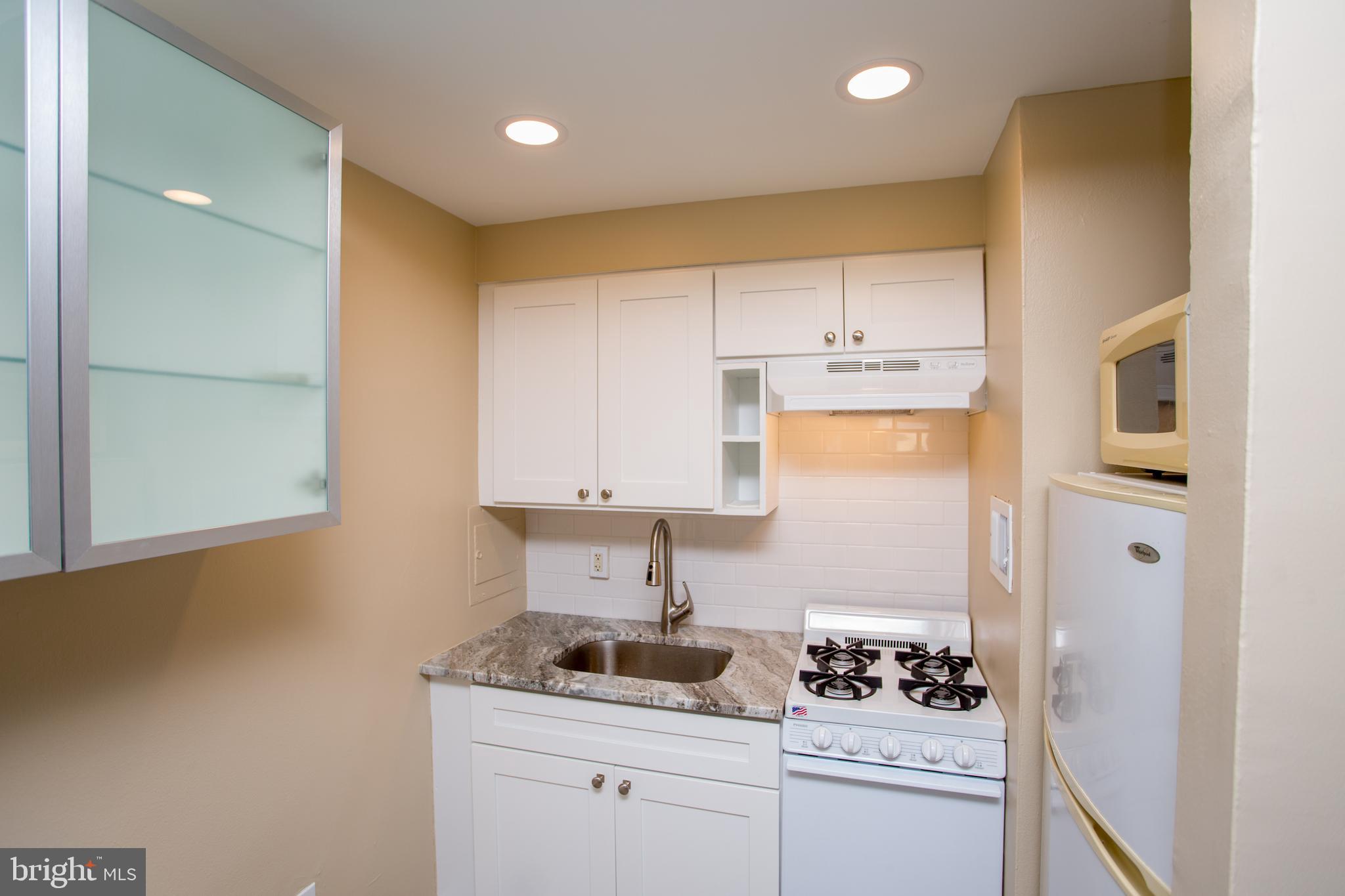 2101-17 Chestnut Street, Unit 1809 Philadelphia, PA 19103 - Photo 22 of 38 a kitchen with white cabinets and appliances