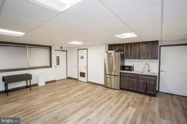 a kitchen with stainless steel appliances kitchen island granite countertop a refrigerator oven a sink dishwasher and white cabinets with wooden floor