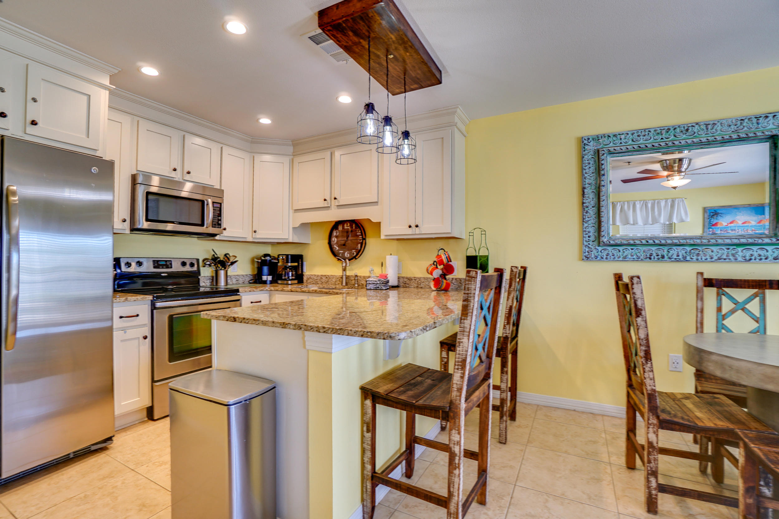 144 Spires Lane, Unit 107 Santa Rosa Beach, FL 32459 - Photo 7 of 17 a kitchen with stainless steel appliances granite countertop a stove top oven a sink a dining table and chairs with wooden floor