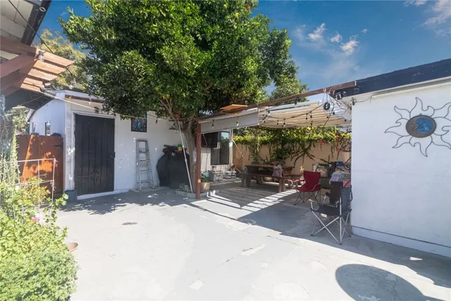a view of a patio with table and chairs under an umbrella with large trees