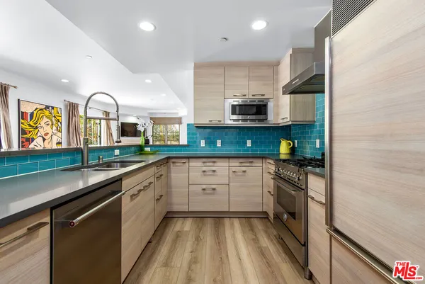 a large kitchen with stainless steel appliances granite countertop a stove a sink and a microwave