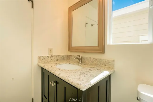 a bathroom with a granite countertop sink and a mirror